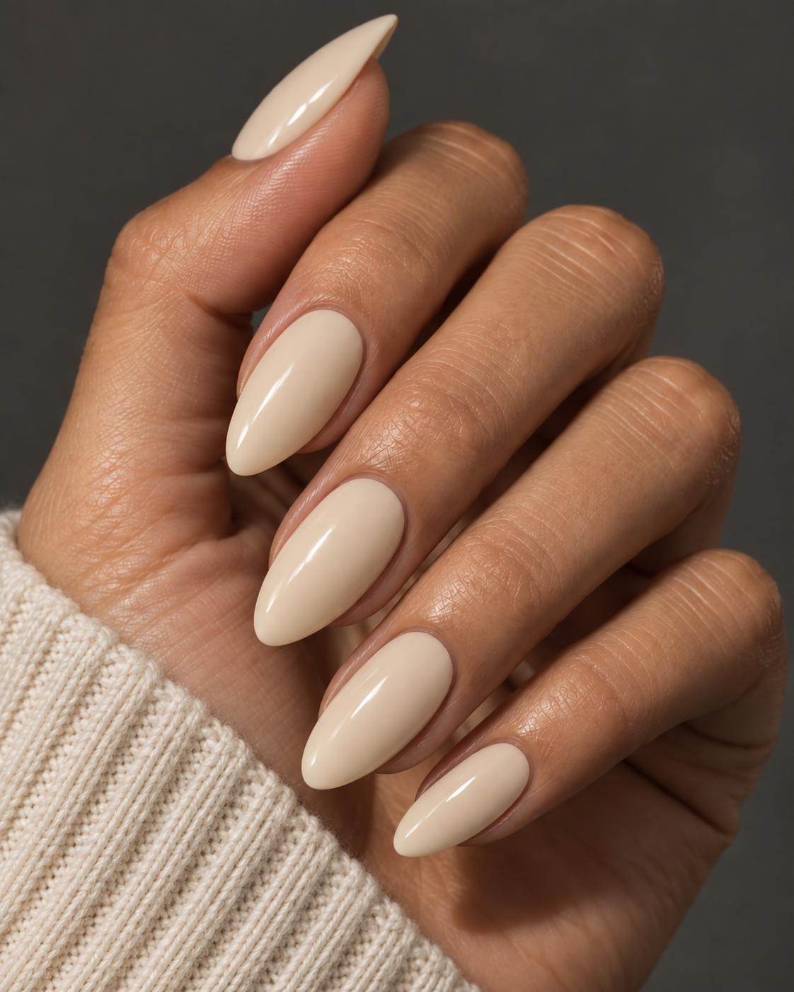 Warm beige BONE almond nails worn with an ivory knit sleeve.