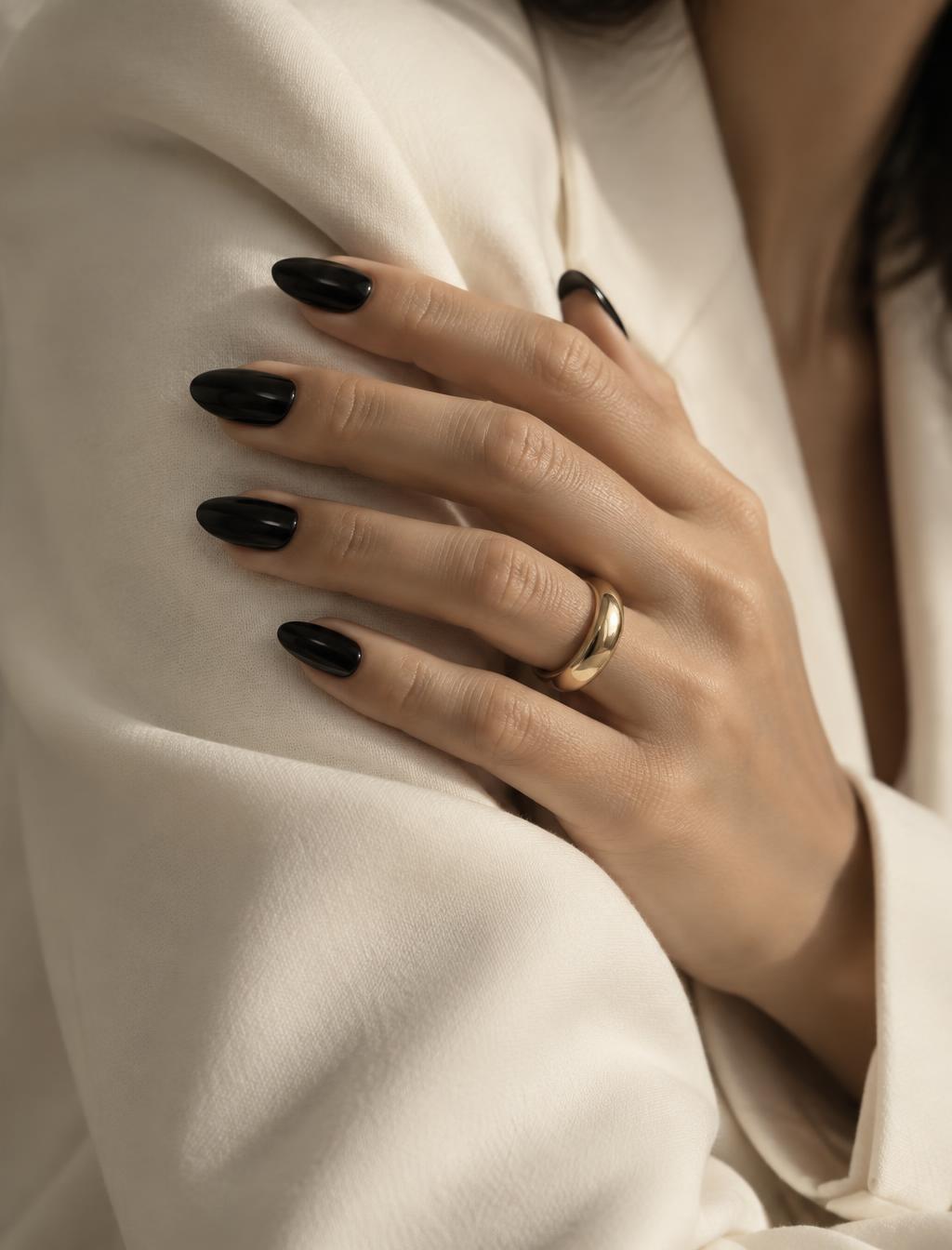 Hand against an ivory sleeve wearing SET. 004 NOIR deep glossy black almond nails.